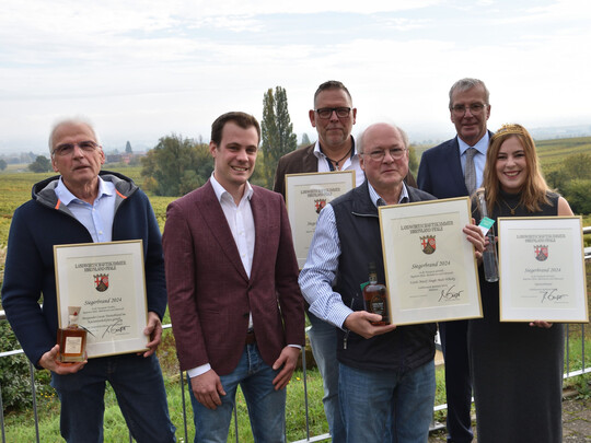 Die Pflzische Weinknigin Denise Stripf, Lucas Mhlhuser vom Pflzer Brennerverband und Kammerprsident konomierat Michael Horper freuen sich mit den glcklichen Brennern.