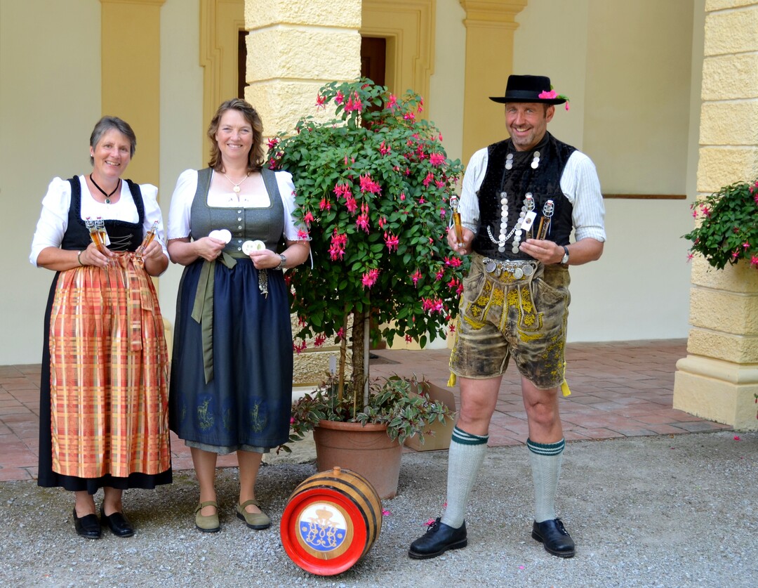 Gärtnermeisterin und Fuchsienspezialistin Jasmin Wolff (mit Medaillen), Hofgarten-und Brennereimitarbeiterin Sabine Behrens sowie Hofgarten– und Brennereileiter Alexander Bauer freuen sich über die Pracht und den neuen Fuchsienlikör aus der Schleißheimer Schlossbrennerei.