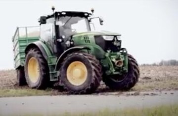 Ein Schlepper mit Hnger fhrt vom Feld auf die Landstrae.